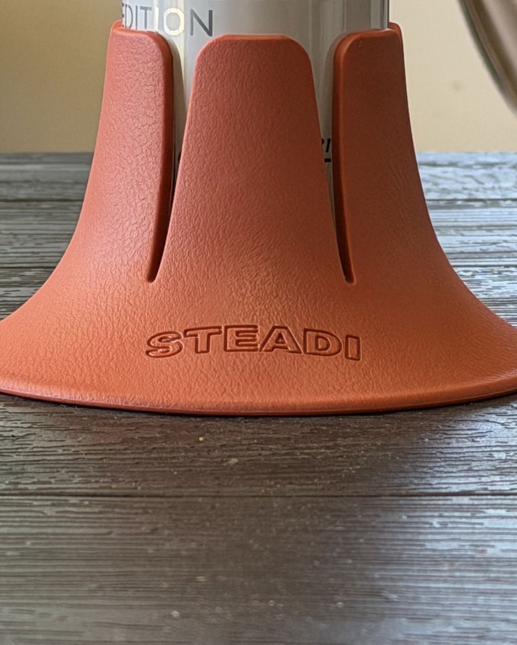 A tall can seated in a terracotta Steadi, the six fins gripping the bottom inch of the can.